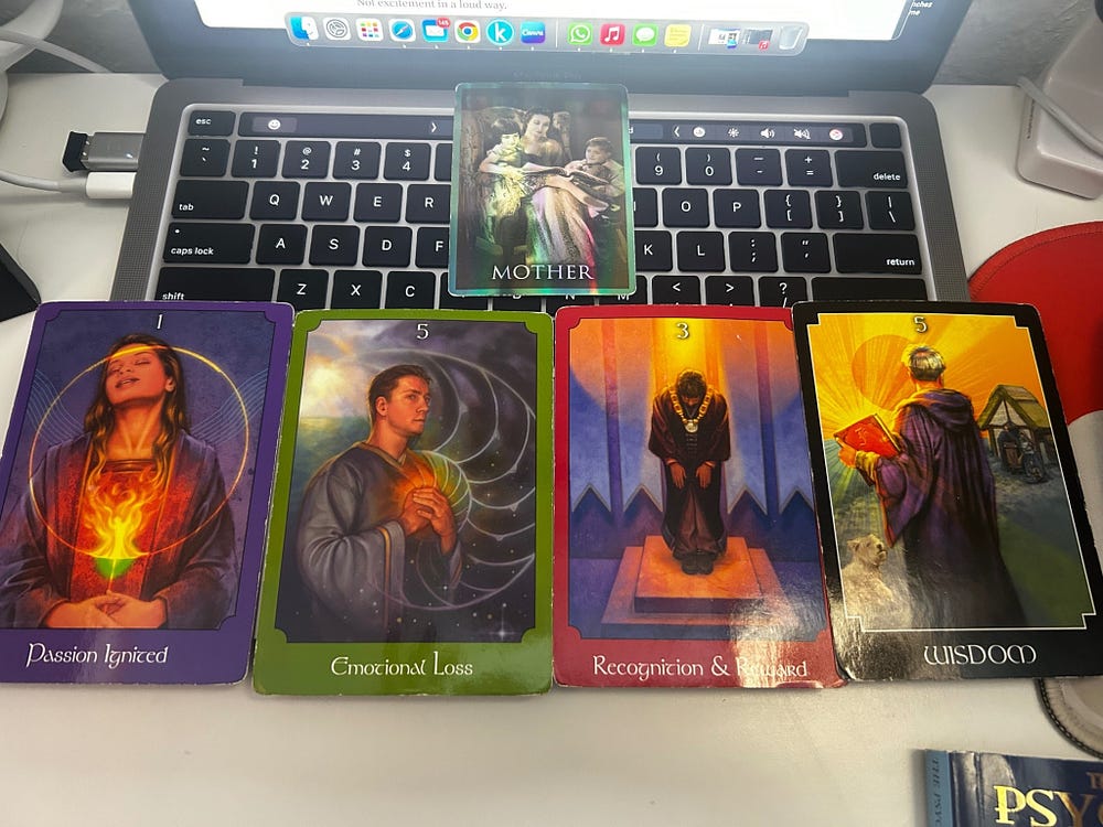 Spiritual tarot spread laid out on a desk, showing cards about passion, loss, wisdom, recognition, and ancestral connection during a personal reading.