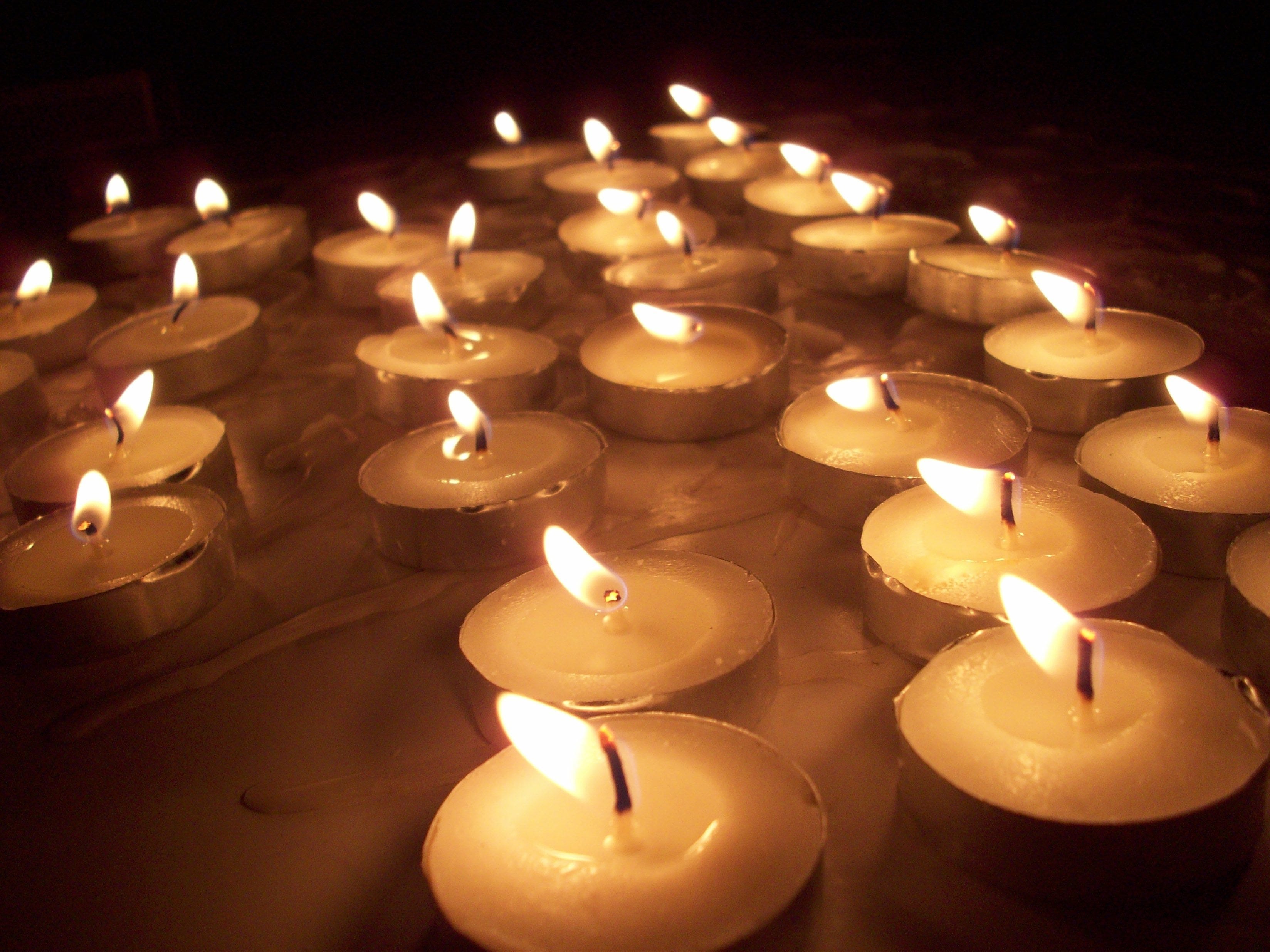 White memorial candles glowing softly in darkness during a Holocaust remembrance ceremony, symbolizing memory, mourning, peace, and the lives lost during World War II.